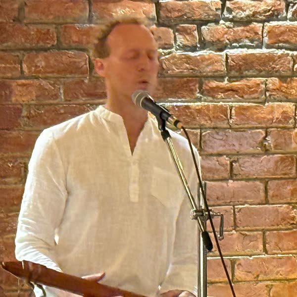 Tomas singing a mantra at the microphone, leading kirtan